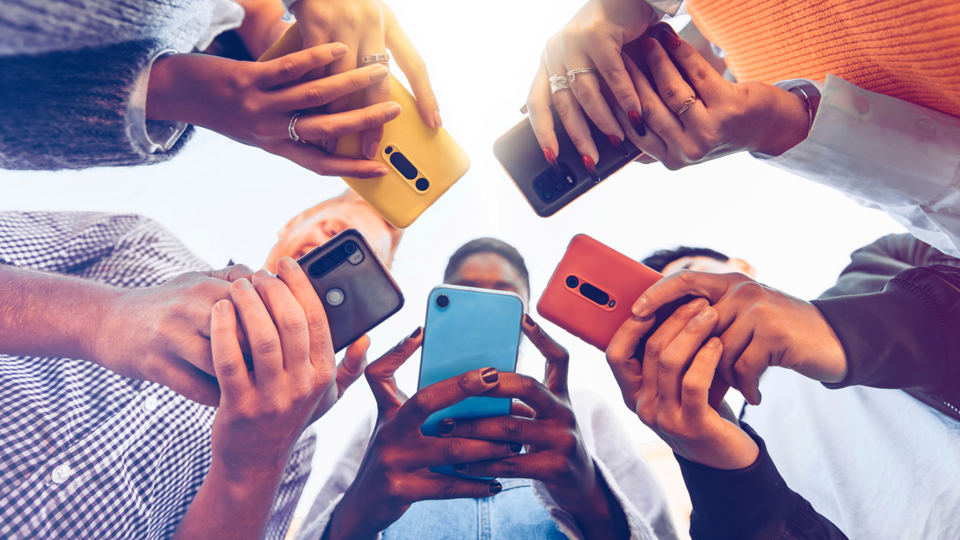 Group of people standing in a circle, each using their own smartphone.