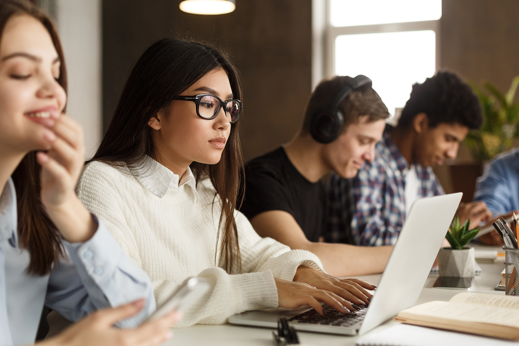 A photo of a diverse group of college students studying on laptops.