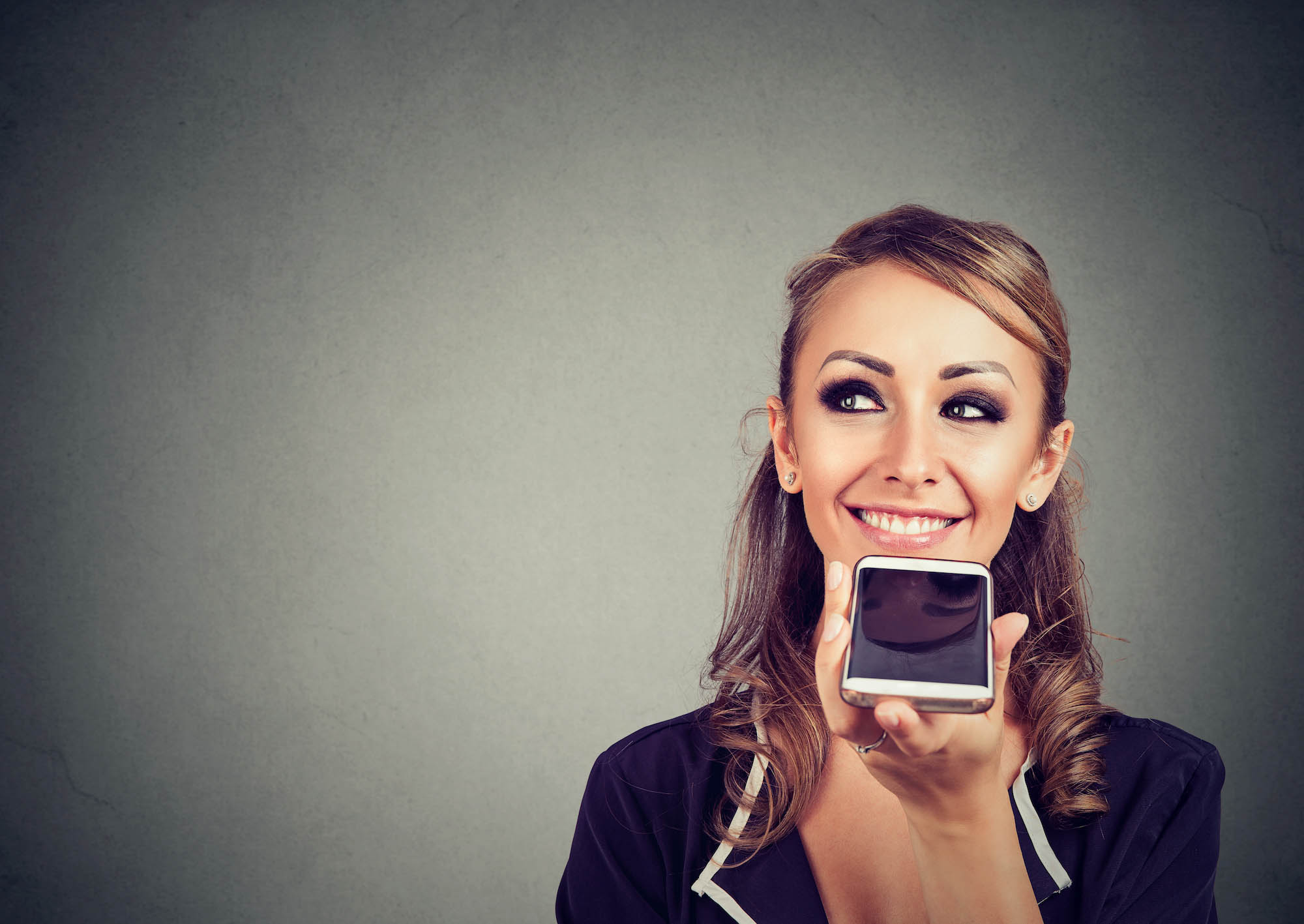 Smiling woman using voice command on her phone.